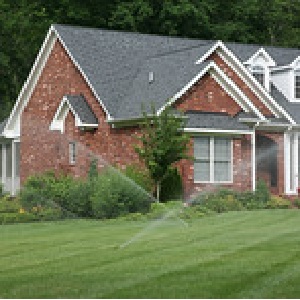 Photo of sprinkler system watering green grass